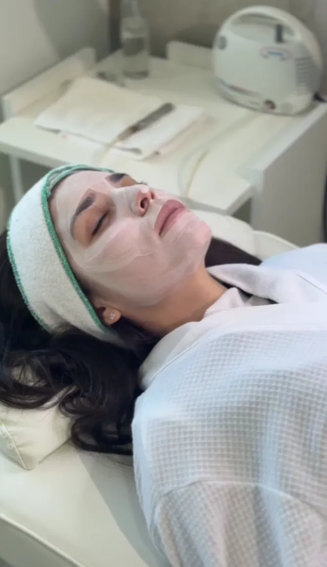 Clienta con máscara hidratante en el gabinete facial después de un peeling